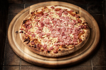 Pizza with ham and mozzarella cheese on wooden background. Soft focus. Close up	