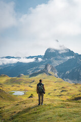 A solitary traveler stands in awe as they gaze at the majestic mountains, fully embracing the...
