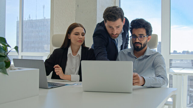 Diverse team corporate coworkers working laptops in office male business coach mentor boss businessman helping employees with computer work training new workers help interns check explain data project