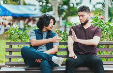Disgusted guy sitting refusing a cigarette. Young man sitting refusing a cigarette in the park