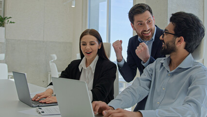Happy creative team celebrate victory in office successful sales stock market data online business people businessmen and businesswoman winning teambuilding corporate teamwork with documents laptop