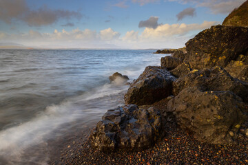 Waves crashing on a pebble beach at Ganavan, near Oban, West Highland, Scotland, UK.