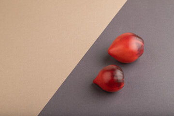 Red Heart shape tomatoes on gray and beige pastel paper. Side view, copy space