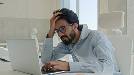 Fototapeta premium Upset frustrated Arabian muslim guy businessman male worker employee manager stressed Indian business man looking at laptop pc at office stress problem with computer fail loss bankrupt failure trouble
