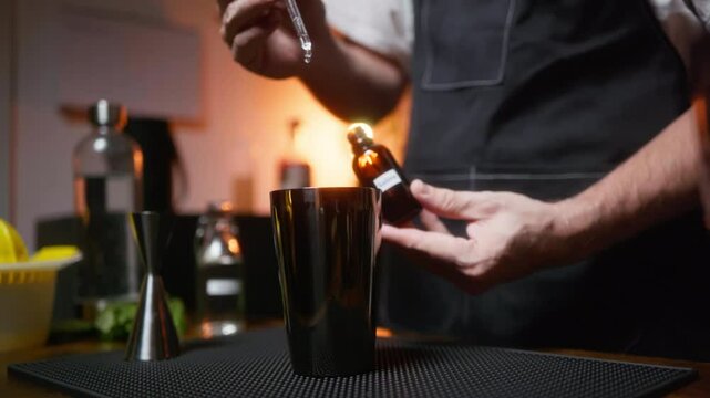 Hobby bartender dripping bitters into shaker.