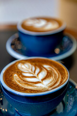 Barista concept, Selective focus of a coffee cup on the table with dark tone, Hot cappuccino or latte art with milk foam on the top, Drinking coffee at the cafe' in the afternoon, Beverage background.