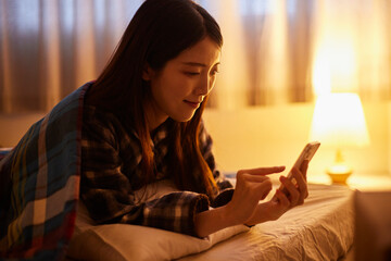 夜の寝室でスマートフォンを使用する日本人の女性 © west_photo