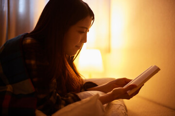 布団を被り読書をする日本人の女性