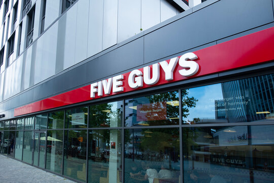 iconic Five Guys restaurant exterior, red sign Five Guys stands out against sleek urban facade, inviting customers to enjoy casual dining experience, Berlin, Germany - August 15, 2024