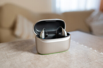 Hearing aid devices resting in charging case on table in living room