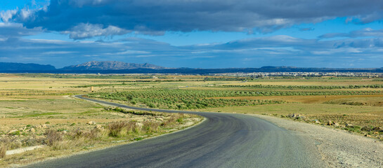 Panoramic landscape picture of the rural countryside of Tunesia, with a road meandering through the middle