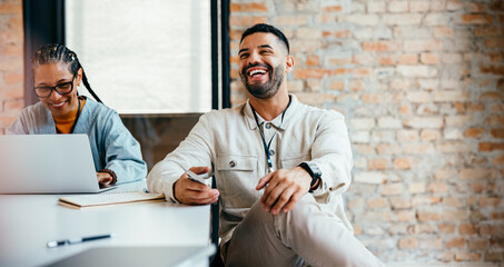 Relaxed businessman enjoying a casual office discussion with a colleague, showcasing a positive and...