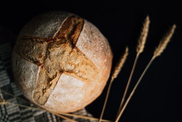 loaf of fresh bread and spikelets on a black background