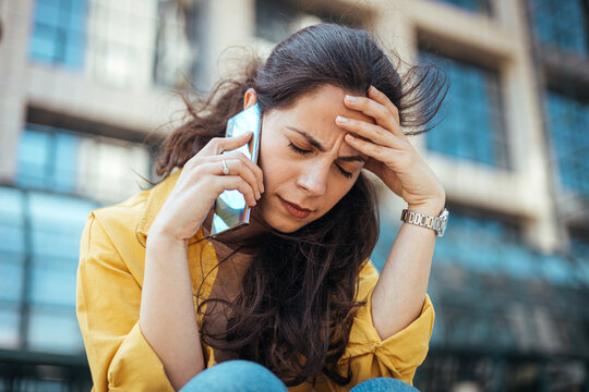 Worried Woman Talking on Smartphone Outdoors in Urban Environment