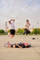 Rollerblading stunt with two men jumping over teammates in a park