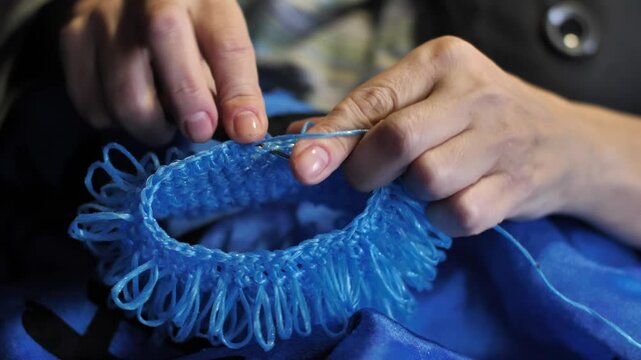 Close-up. Woman's hands crocheting a product made of blue polypropylene nylon plastic twine. Hobby-knitting and handmade crafts for relaxation and mental health