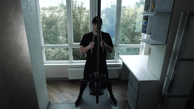 Pumping triceps arms on a sports simulator in an apartment at home. A young man trains his triceps by doing rope rows. Workout at home. Slow motion