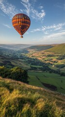 Fototapeta premium Hot air balloon soaring over idyllic valley landscape at sunrise.