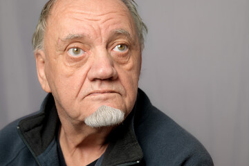 portrait gros plan homme âgé exprimant le mépris fond gris