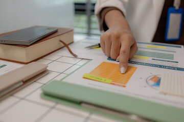there are a lot if documents pied up on the desk if the data analysis team leader, an employee sits...