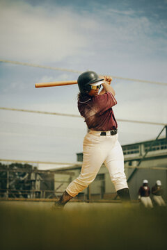 Focused baseball player swinging bat during outdoor practice session on a sunny day