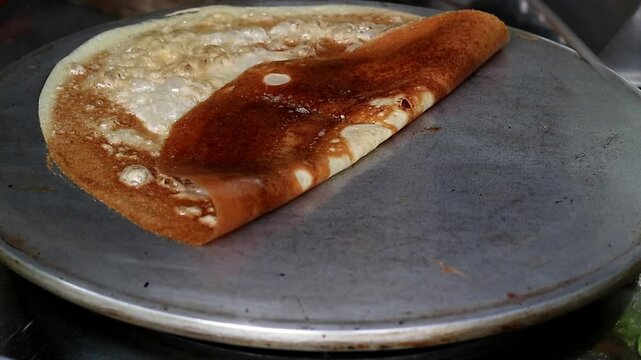 Asian Indonesian adult's hand cooking leker, thin and crispy Indonesian pancake, a sweet and savory treat, popular Indonesian street food 