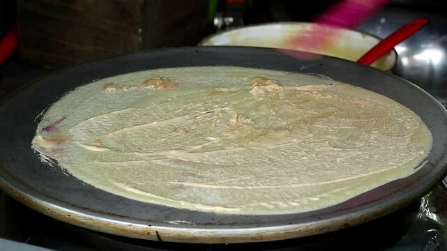 Asian Indonesian adult's hand cooking leker, thin and crispy Indonesian pancake, a sweet and savory treat, popular Indonesian street food 