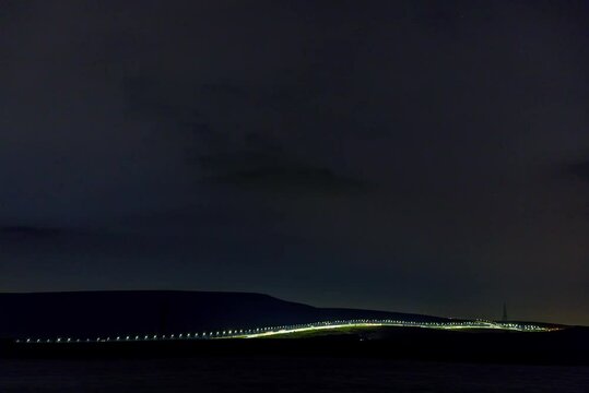 Nighttime Timelapse of M62 Motorway in Front of Reservoir with Moving Stars