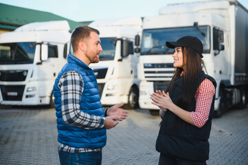 Two professional truck drivers stand in front of the big truck. Male and female truck drivers in...
