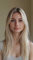 Naklejka premium A young woman with long blonde hair and a gentle smile, posing in a close-up portrait against a neutral background.