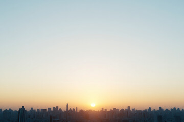 Fototapeta premium A city skyline with a bright orange sun in the sky