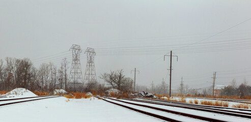 Snow blankets railway tracks surrounding area, while power lines stretch across winter landscape.
