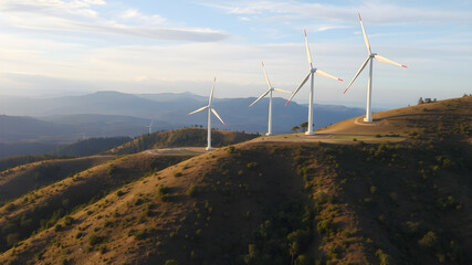 Obraz premium Green energy concept, eco power. Wind turbine located along the hill with the wind blowing all the time. Can produce renewable energy as well. Considered a clean energy.