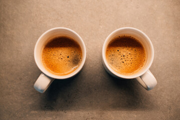 Two white cups with espresso on wood table