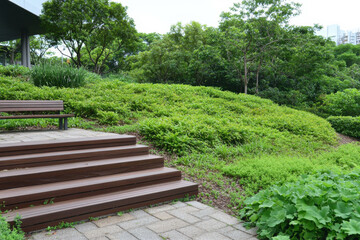 A park with a wooden staircase leading up to a bench