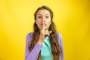Little girl touching finger on lips for quiet