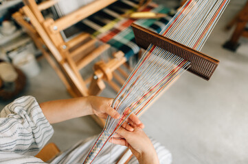 a craftswoman weaves a belt