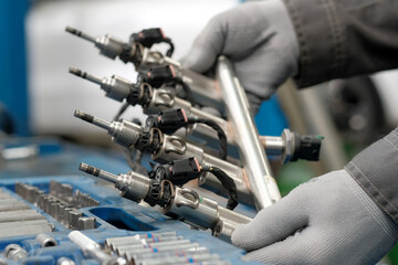 Car service. Engine repair. Fuel frame with injectors. Close-up. The car mechanic performs repair...