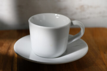 Simple elegance of a white coffee cup on a wooden table in warm morning light