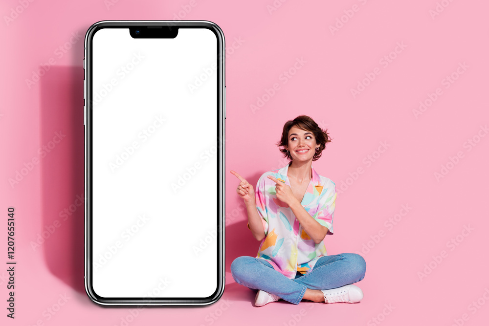 Poster full size photo of pretty young lady point fingers empty space smart phone screen isolated on pink c