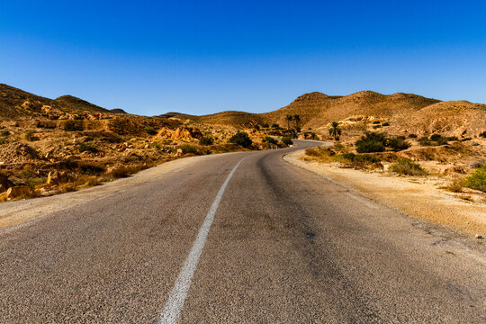 A winding asphalt road in the low mountains of Jebel Matmata. Matmata, Tunisia, Africa