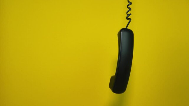 An old telephone receiver hanging on a cord. Planty of space for text. Slow motion