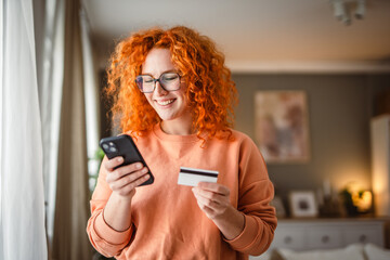 smile redhead woman use mobile phone and credit card for payment