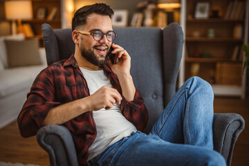 portrait of adult man sit in the armchair and talk on mobile phone