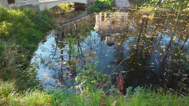 Yellow autumn in Kemeri National Park. A popular walking place in Latvia. Reflection in the pond of the restored architecture of the park. Multicolored clothes of walking tourists on a sunny day.