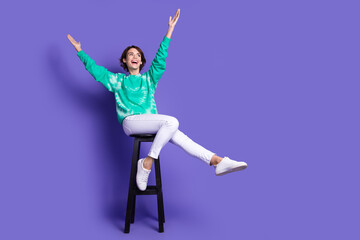 Fototapeta premium Full size photo of young girl sit chair playful have fun look empty space dressed stylish green clothes isolated on violet color background
