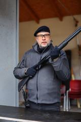 An instructor of shooting in a beret at a shooting range show how to use gun