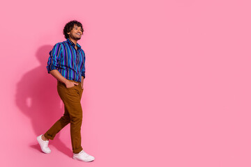 Photo of nice cheerful elegant man wear trendy striped clothes walking empty space isolated on pink...