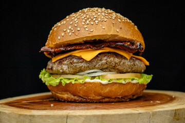 Hambúrguer artesanal com cheddar, molho branco especial, tomate, alface e bacon em tábua de madeira, Artisan hamburger with cheddar, special white sauce, tomato, lettuce, and bacon on wooden board