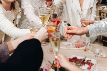 Group of guests celebrate and raise glasses, toasting and cheering with alcohol glasses with wine...